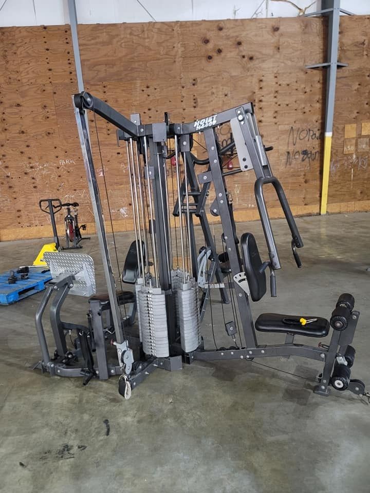 Multi-functional gym equipment set up in an industrial space with concrete floor and plywood walls.