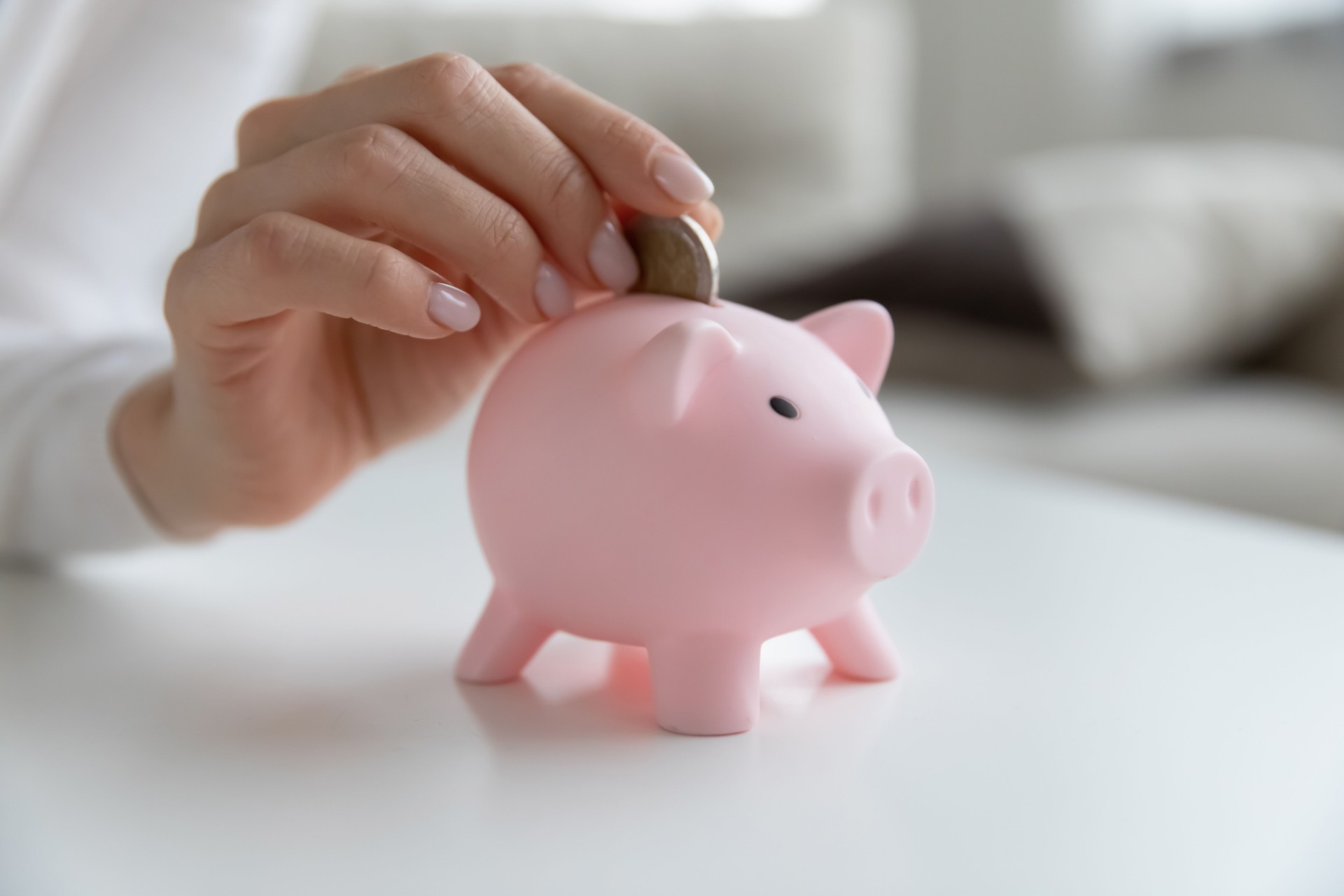 Close up of woman put coin in piggybank saving